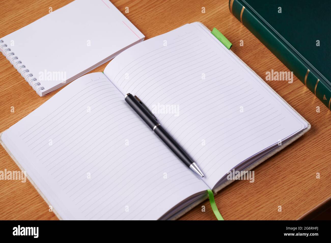 Plain Blank Open Notebooks With Stack Of Pens Inside Container Placed On Top Of A Table. Simple Empty Lined Notepads Beside A Holder Of Colorful Stock Photo