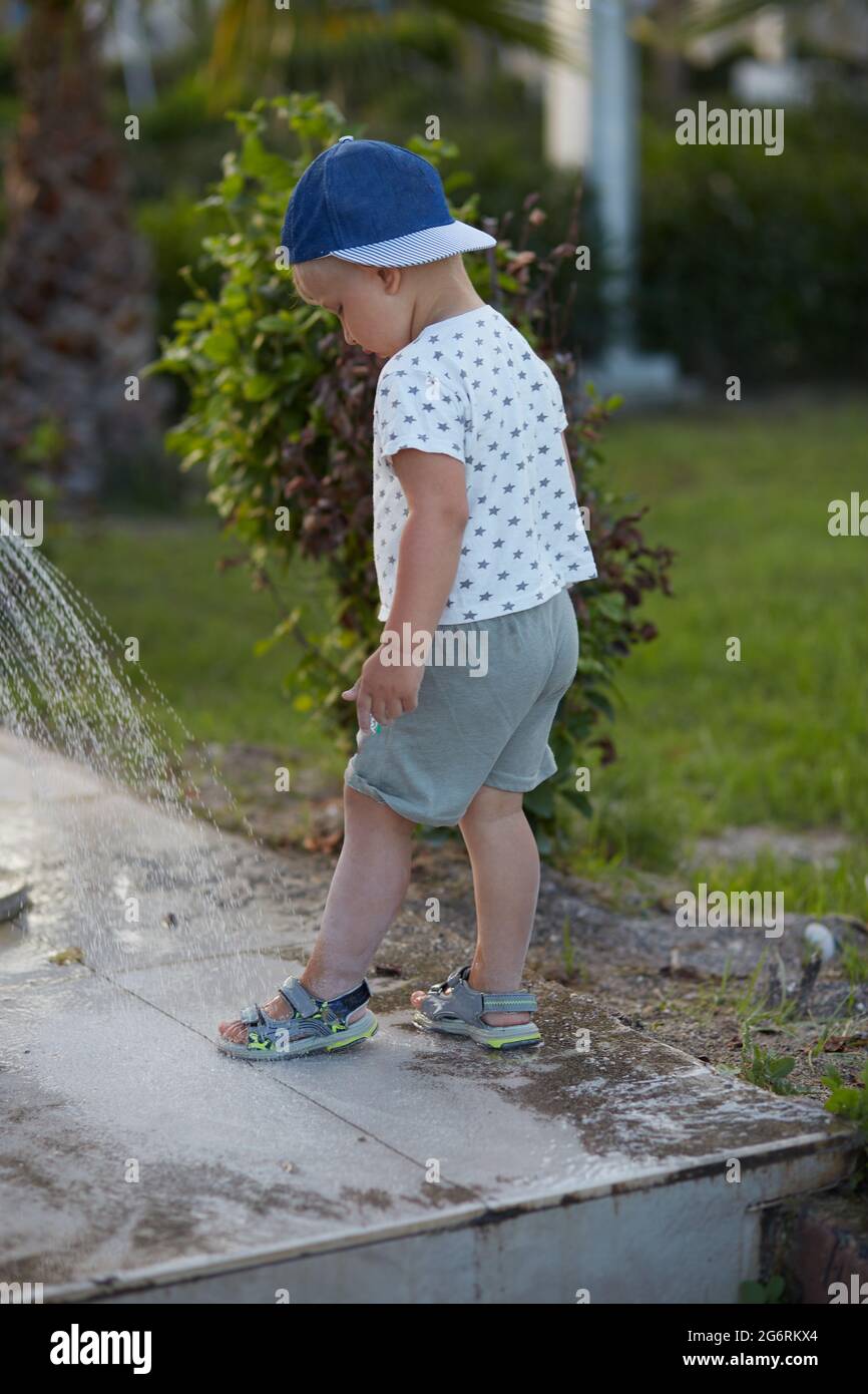 Toddler in the cap wash his legs under summer shower after salt water