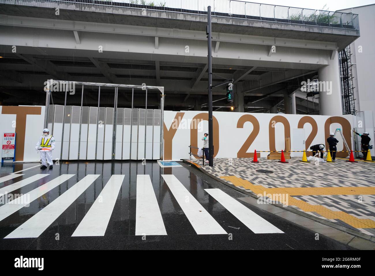 Tokyo, Japan. 8th July, 2020. Workers are seen putting up Tokyo 2020 signage along a wall at the New National Stadium. Japanese Prime Minister Yoshihide Suga announced a fourth state of emergency for Tokyo in which this new state of emergency will go in effect from Monday until August 22. This means the Olympics will be held under emergency measures. Credit: AFLO/Alamy Live News Stock Photo