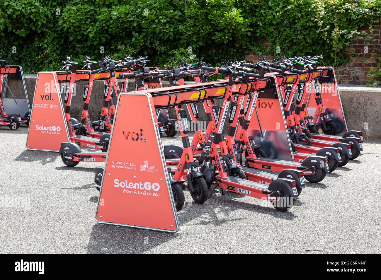 A Voi e-Scooter parking station filled with scooters for hire Stock Photo