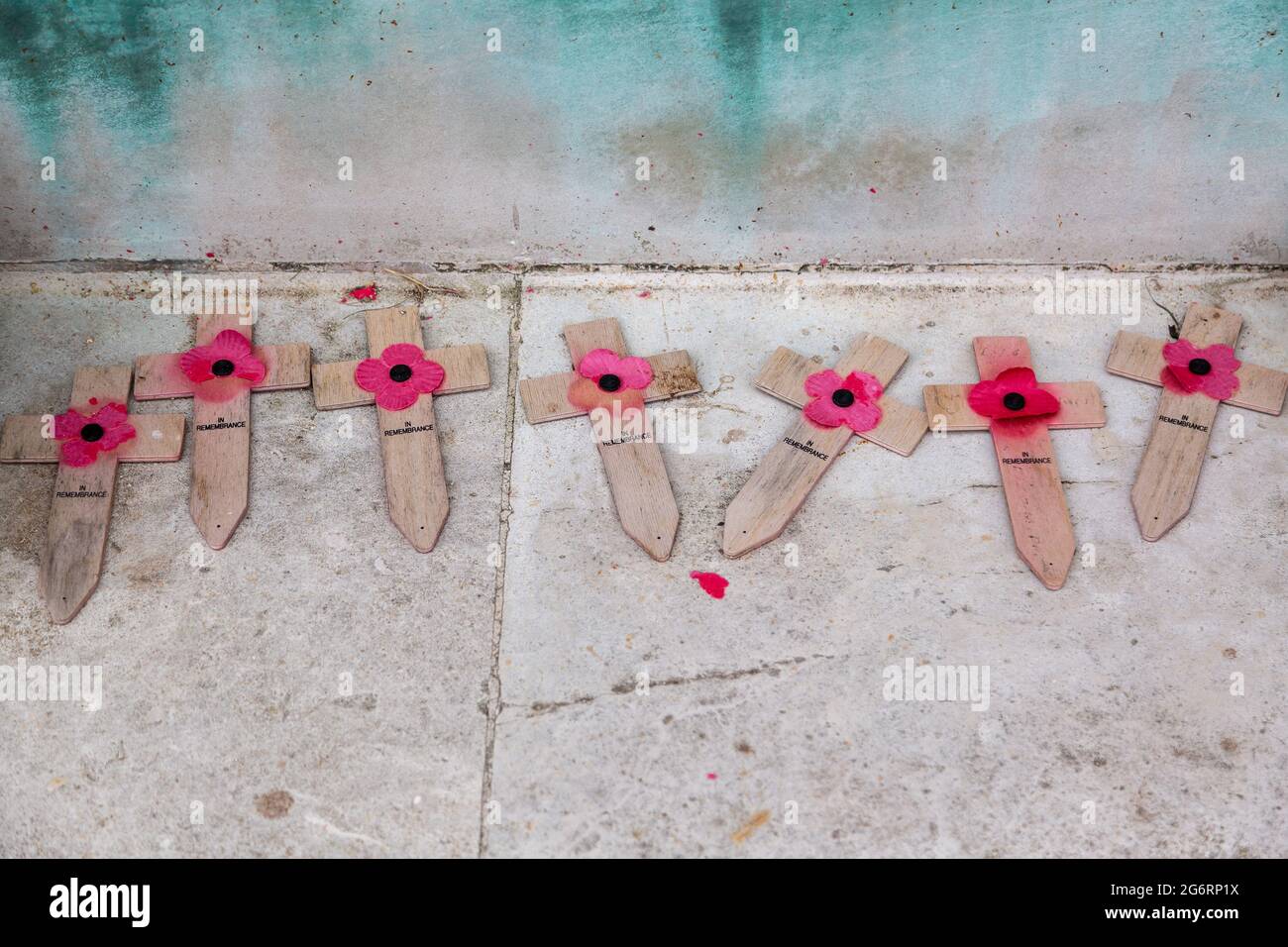 Weathered wooden crossed with faded red poppies laid at a war memorial Stock Photo