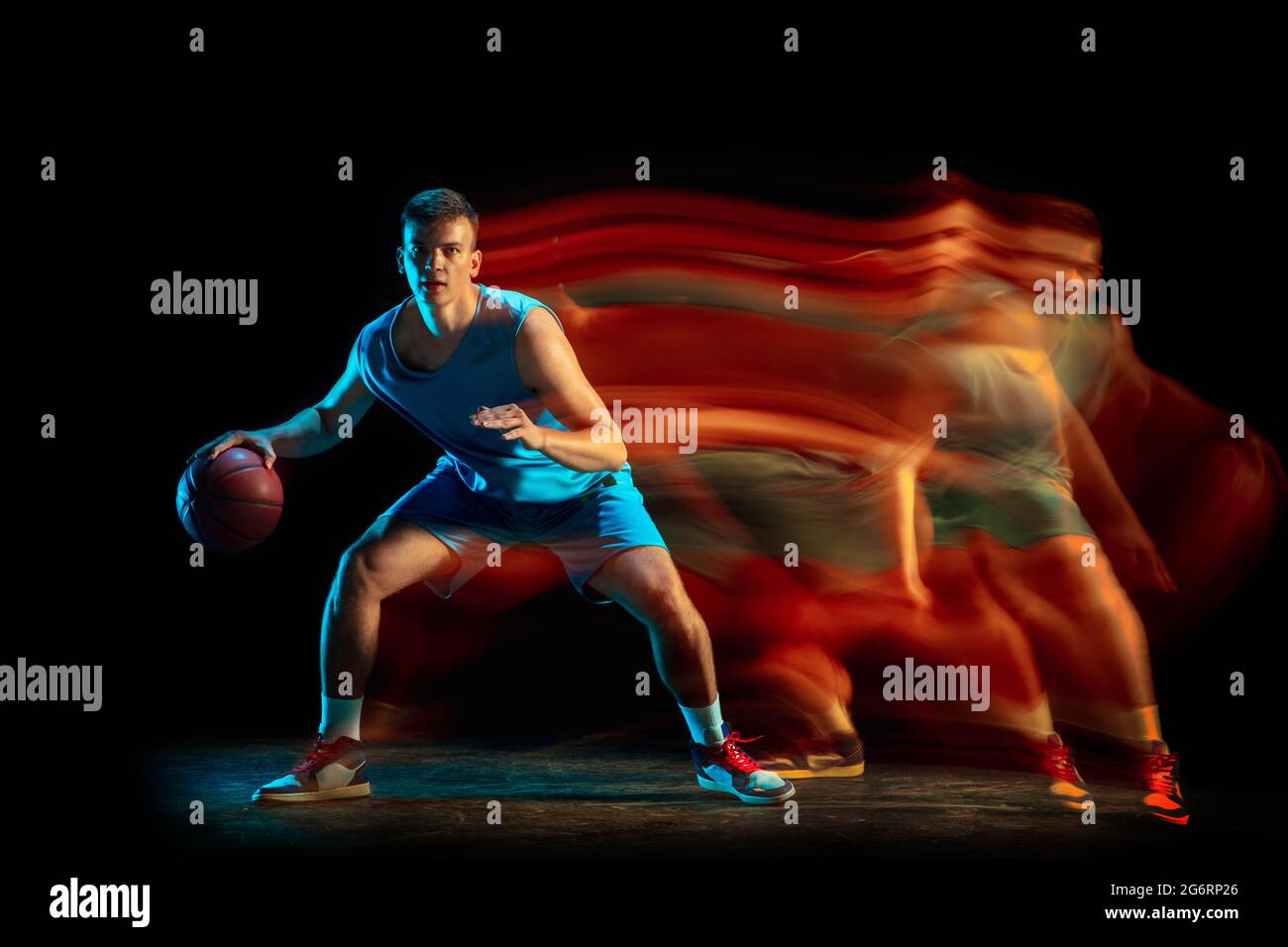 Professional male basketball player in blue uniform playing basketball isolated over dark studio background in mixed light. Concept of healthy Stock Photo