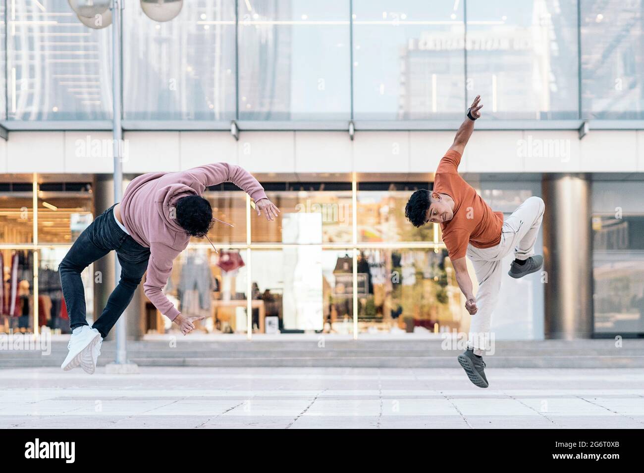 Talented young boys doing break dance in the street and having fun. They are doing coordinated moves. Stock Photo