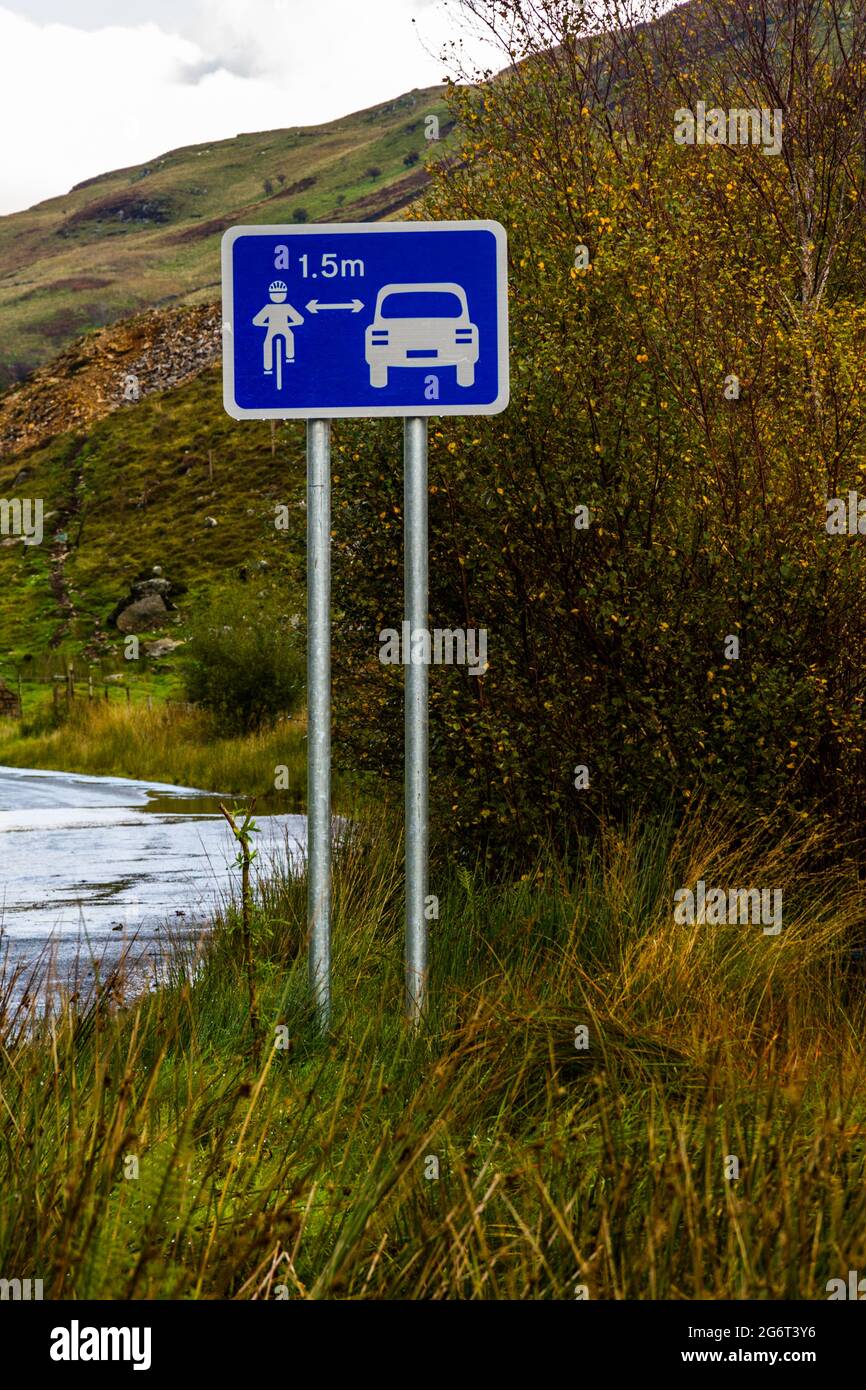 Sign in country of UK Wales. Showing car keeping 1.5 metres from cyclist, portrait. Stock Photo