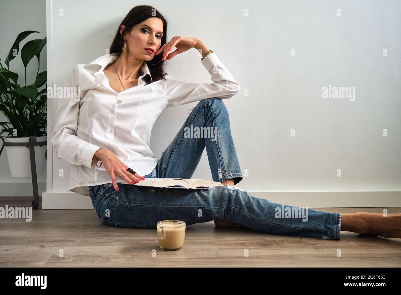 a young girl is sitting on the floor with a cup of coffee Stock Photo ...