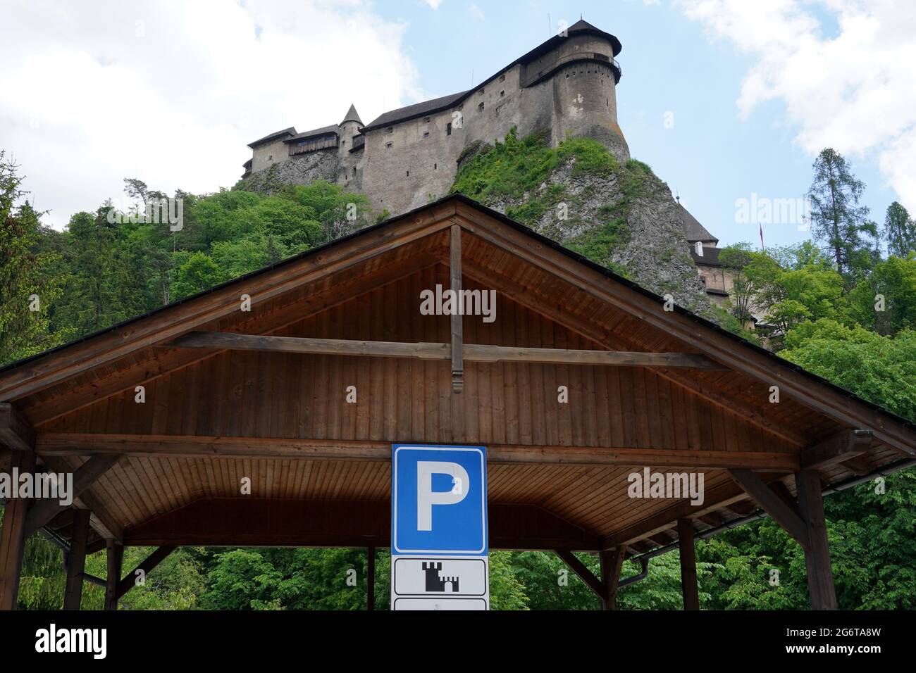 Parking booth made of wood with traffic sign for parking in area around Orava castle in Slovakia. Low angle view with the silhouette of a castle. Stock Photo