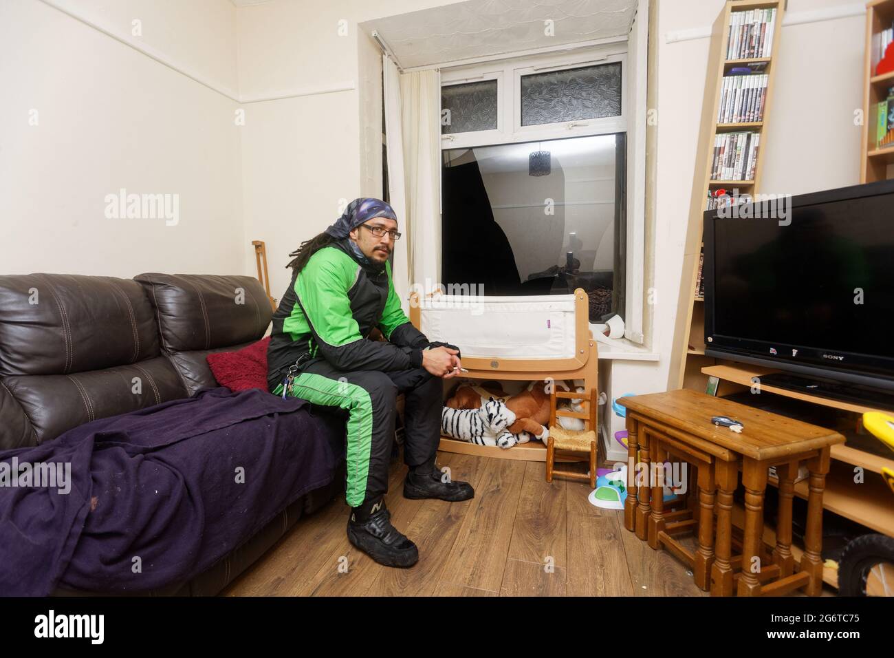 Pictured Adam Romain by the smashed window in the front room of his