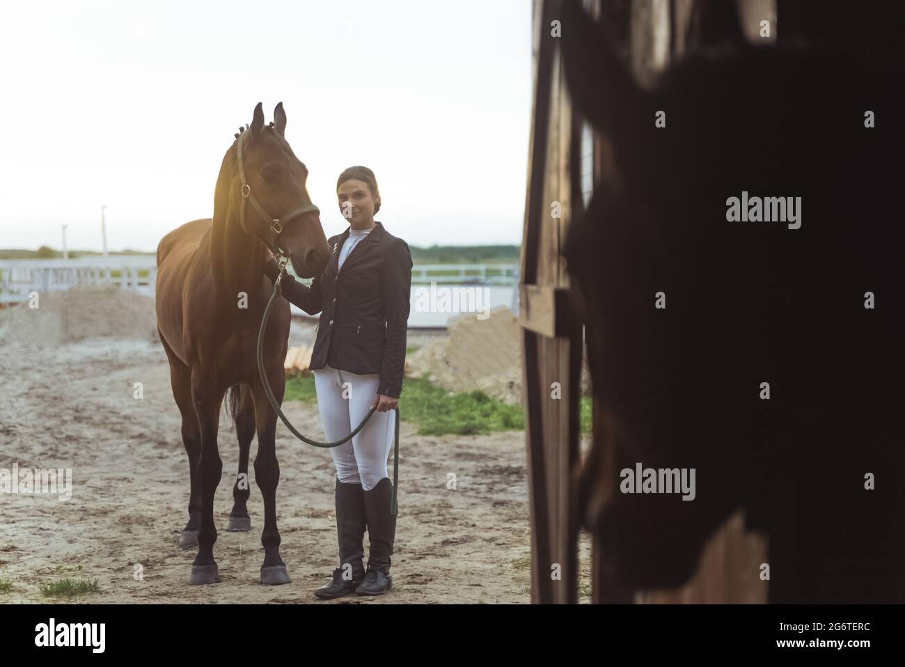 Horse woman standing with her dark Bay horse outside the stable. Posing ...