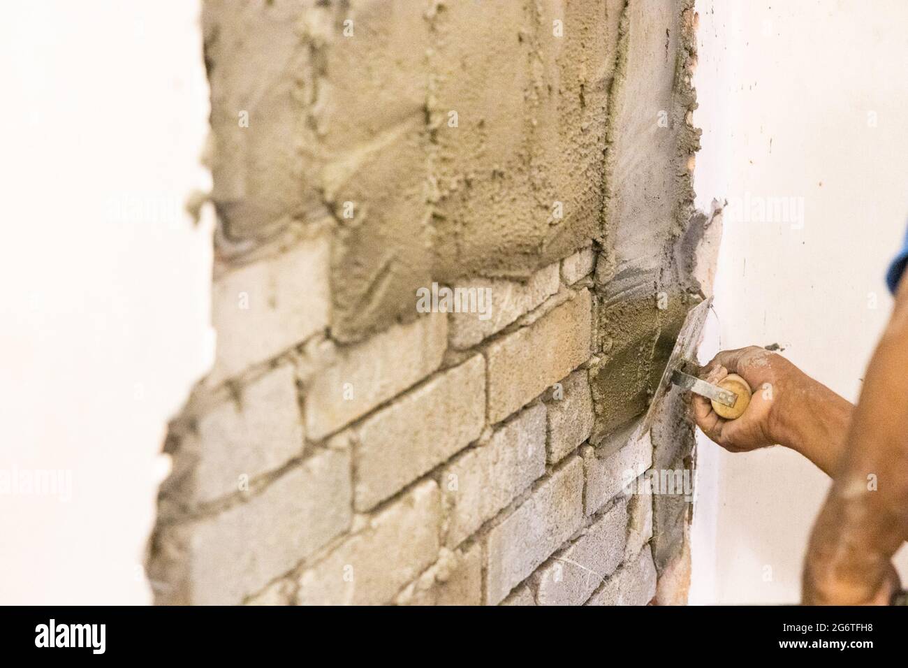 Worker plastering cement mortar on brick wall with trowel Stock Photo