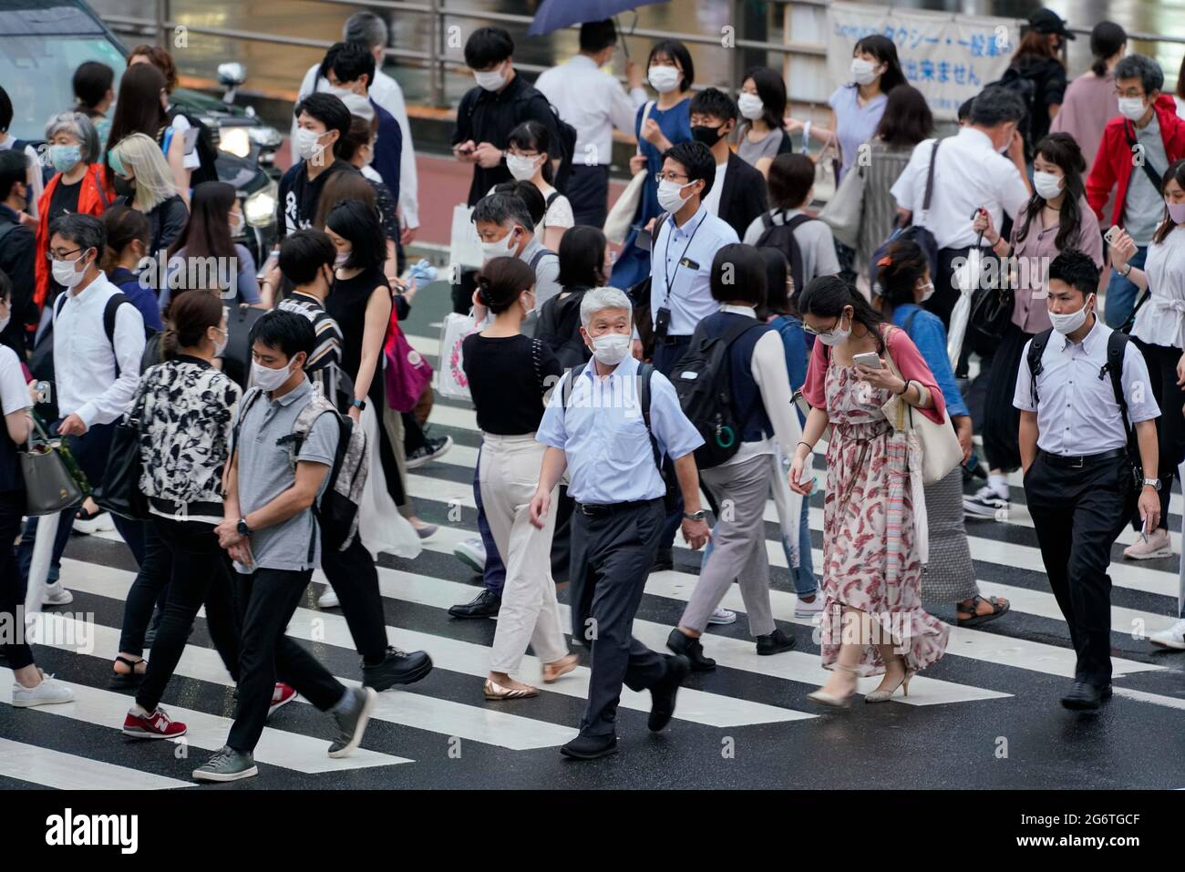 Tokyo. 8th July, 2021. Pedestrians walk across a street in Tokyo, Japan on July 8, 2021. The Japanese government decided Thursday to put capital Tokyo under the fourth state of emergency over COVID-19, covering the duration of the Olympics, in an effort to curb a recent surge in infections. Credit: Christopher Jue/Xinhua/Alamy Live News Stock Photo
