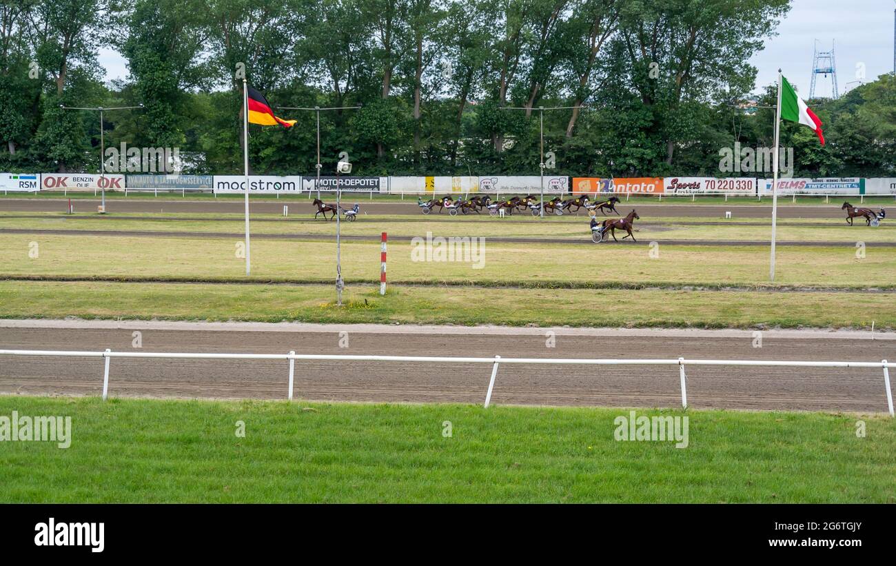 Aarhus, Denmark - 27 June 2021: People watch trotting derby, Sunshine on the trotting track. Horses, Jocky, Sulky Stock Photo