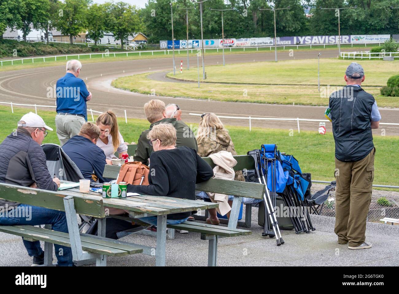 Aarhus, Denmark - 27 June 2021: People watch trotting derby, Sunshine on the trotting track. Horses, Jocky, Sulky Stock Photo