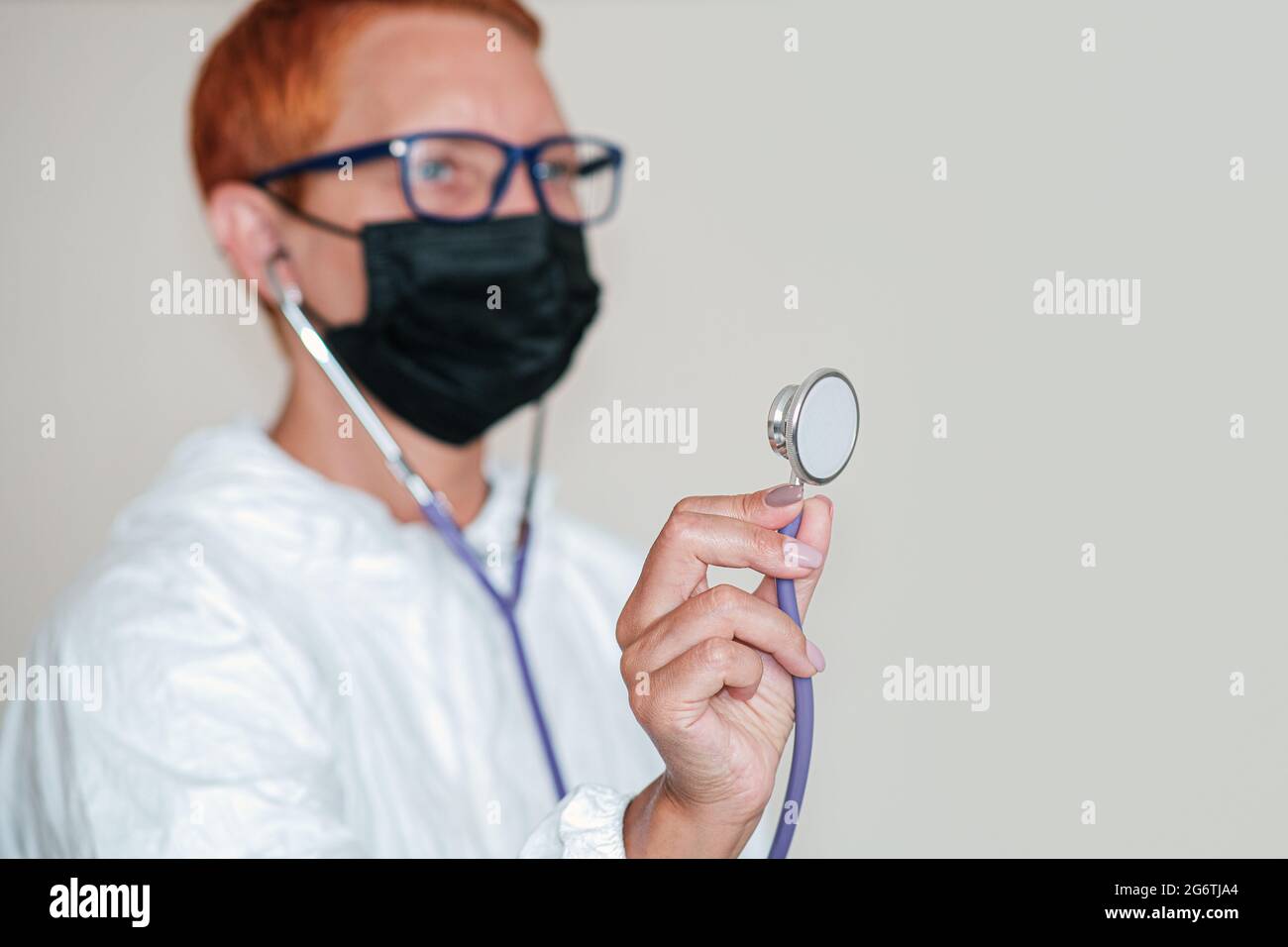 A female doctor in a black protective mask on her face holds a stethoscope in her hand Stock Photo