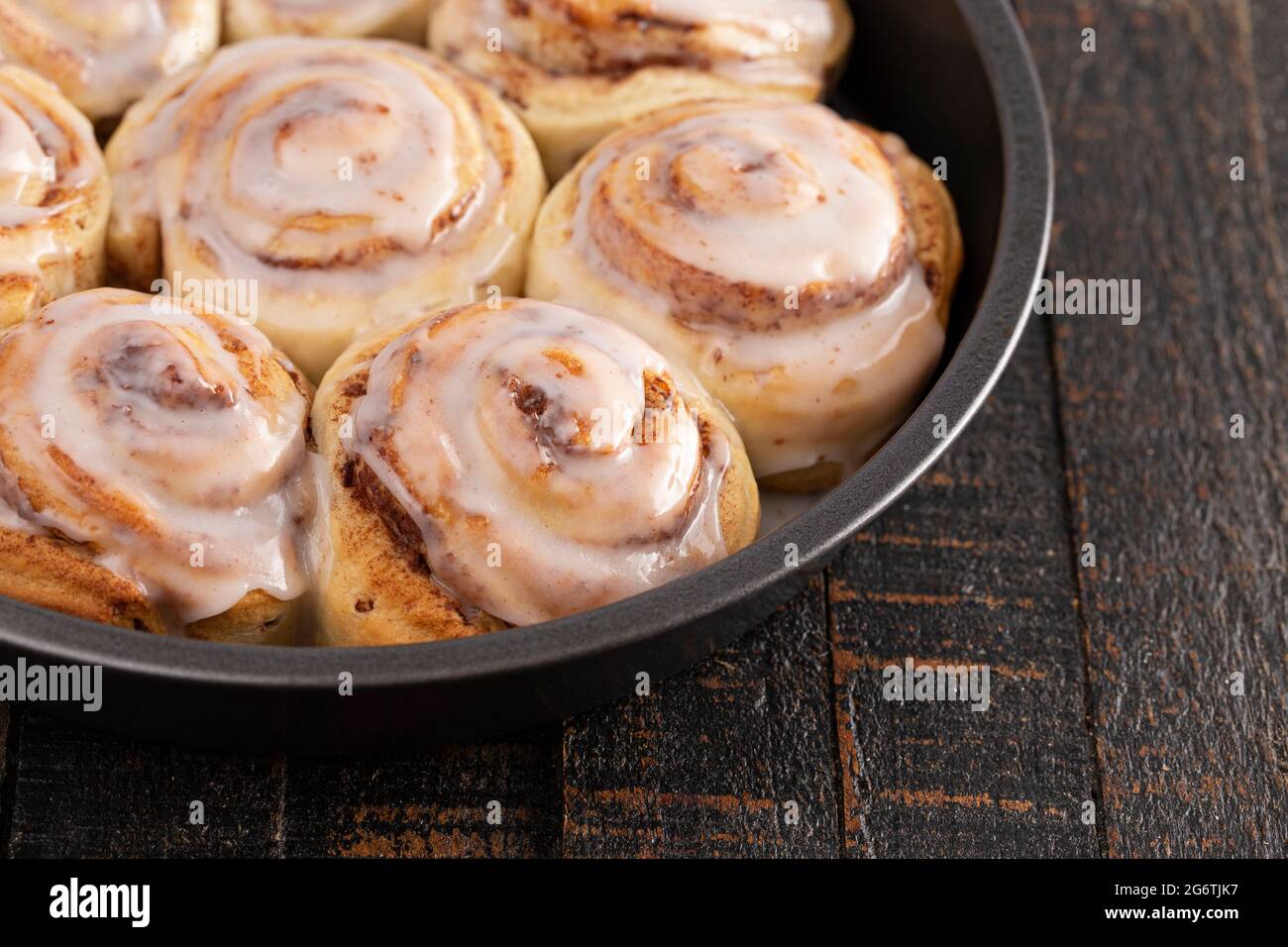 Frosted Cinnamon Rolls in a Pan on a Rustic Wooden Table Stock Photo