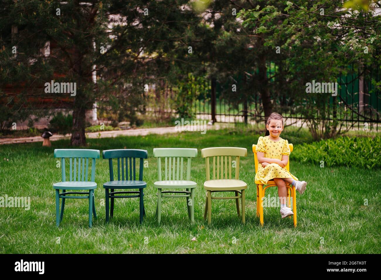 lifestyle portrait of a girl in dresses sitting on chairs in an open-air cinema in the backyard, family vacation on weekends on summer evenings Stock Photo