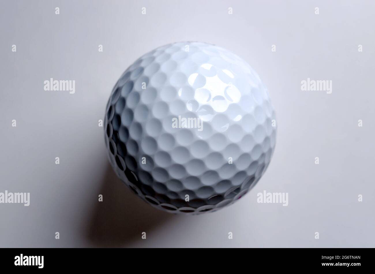 Single white golf ball from above. American golf ball with special notches, designed to be used in the game of golf. Photo. Stock Photo