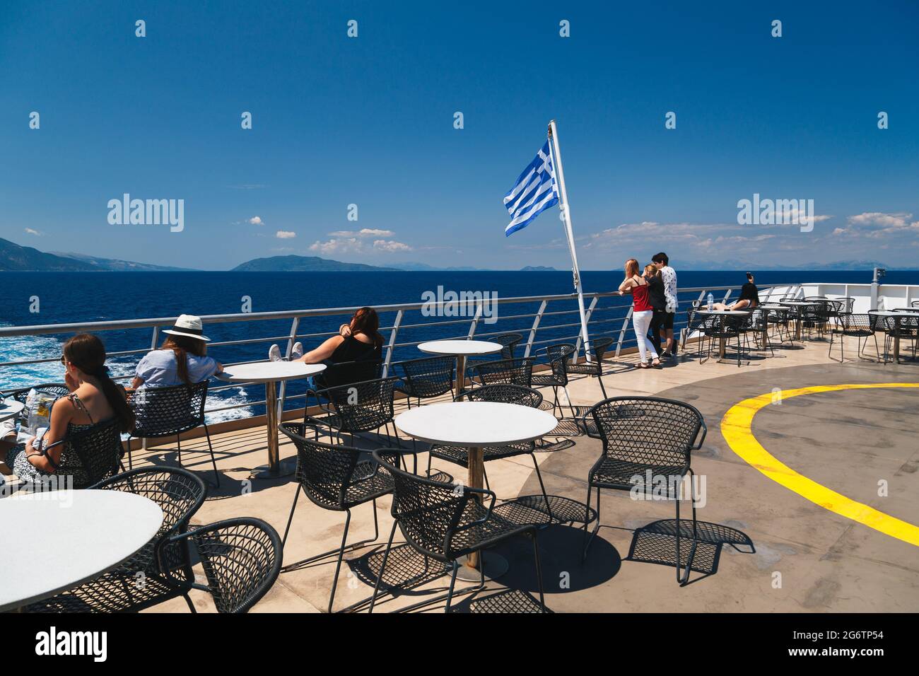 Poros, Cephalonia island, Greece - July, 17 2019: Passengers of the cruise ship relaxing at open deck aft and looking at mountain landscape of Stock Photo