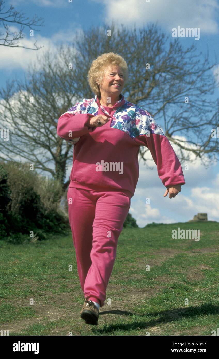 mature woman walking briskly in countryside Stock Photo