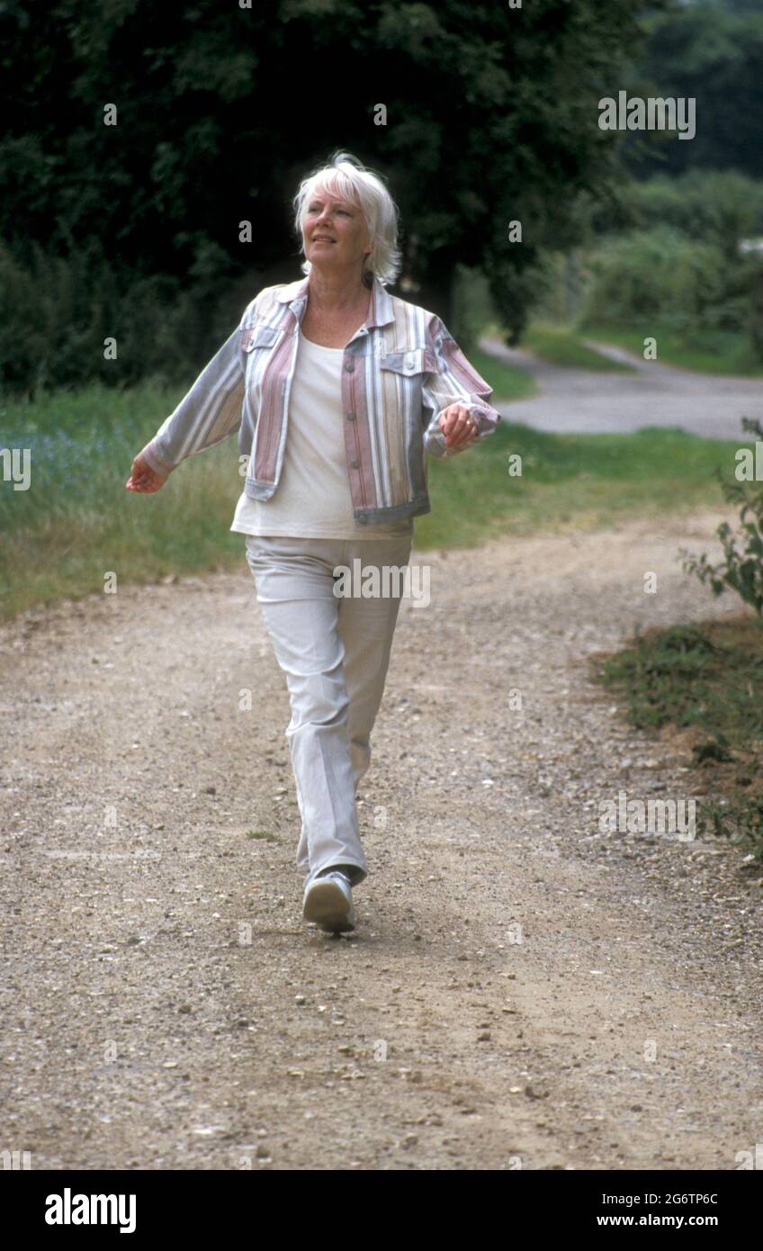 mature woman walking alone in countryside Stock Photo