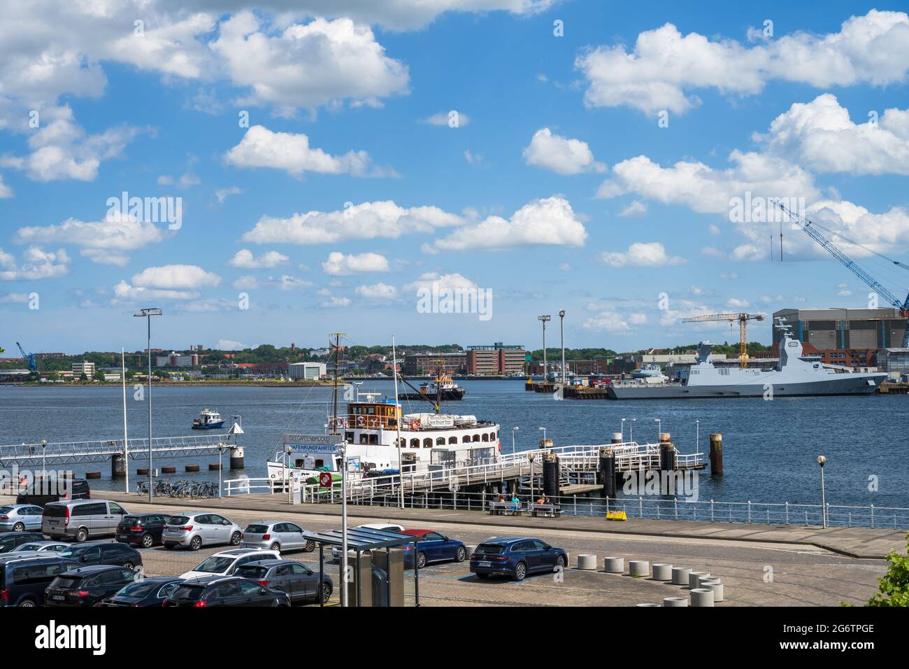 Blick über die Kieler Innenförde zu den Werften, Im Vordergrund die Seegartenbrücke mit dem Traditionsschiff MS Stadt Kiel Stock Photo