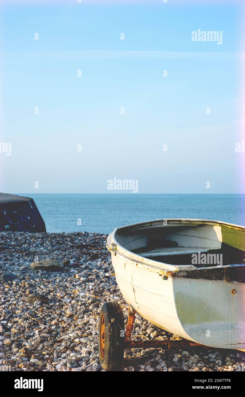 Small boat on a pebble beach in Lyme Regis, Dorset, England, UK Stock Photo