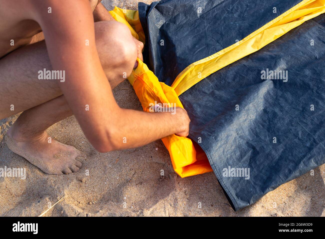 A man is folding a tourist tent. Summer vacation in nature, on the seashore. Stock Photo