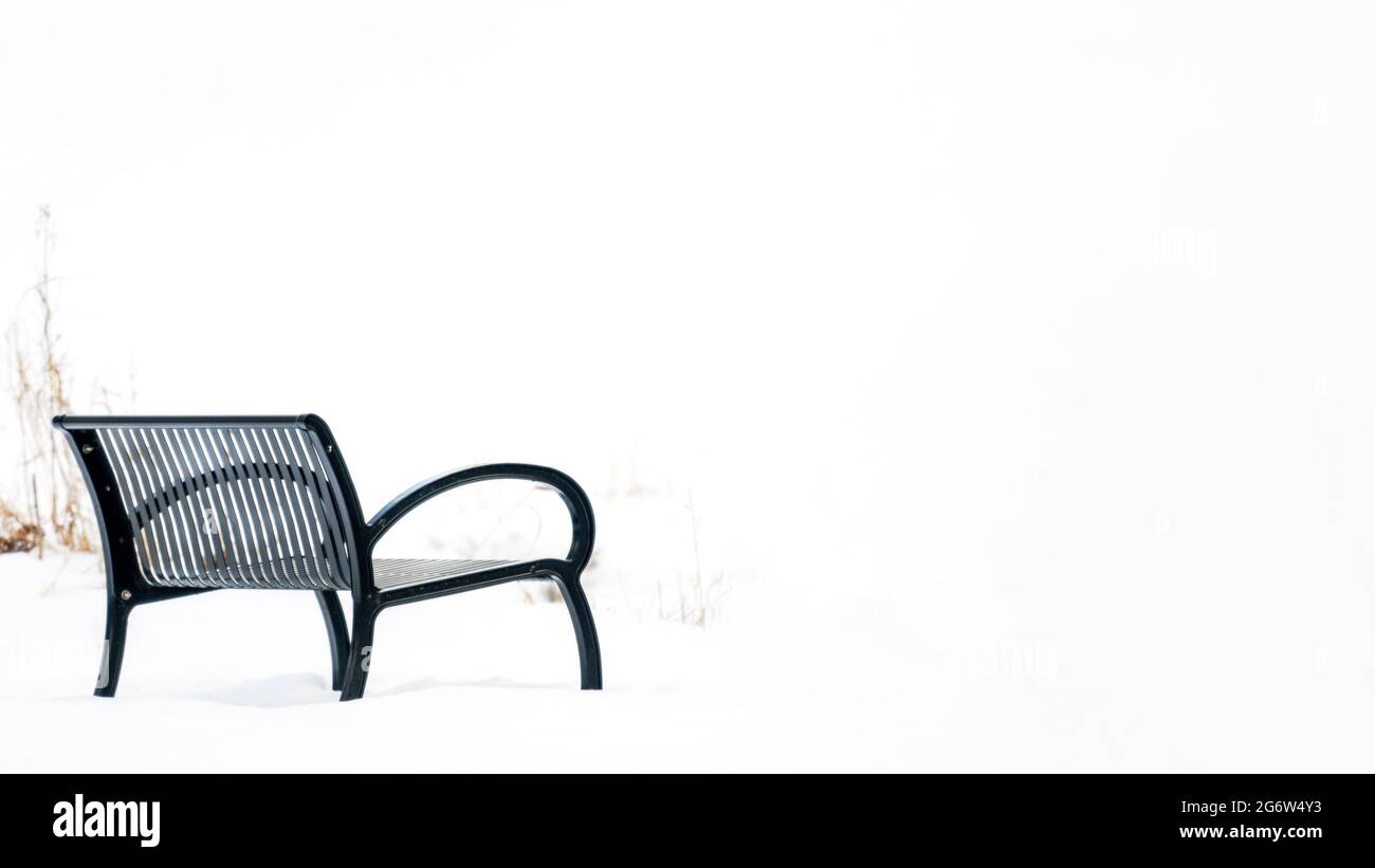 A bench sits in stark contrast to the snow. Stock Photo