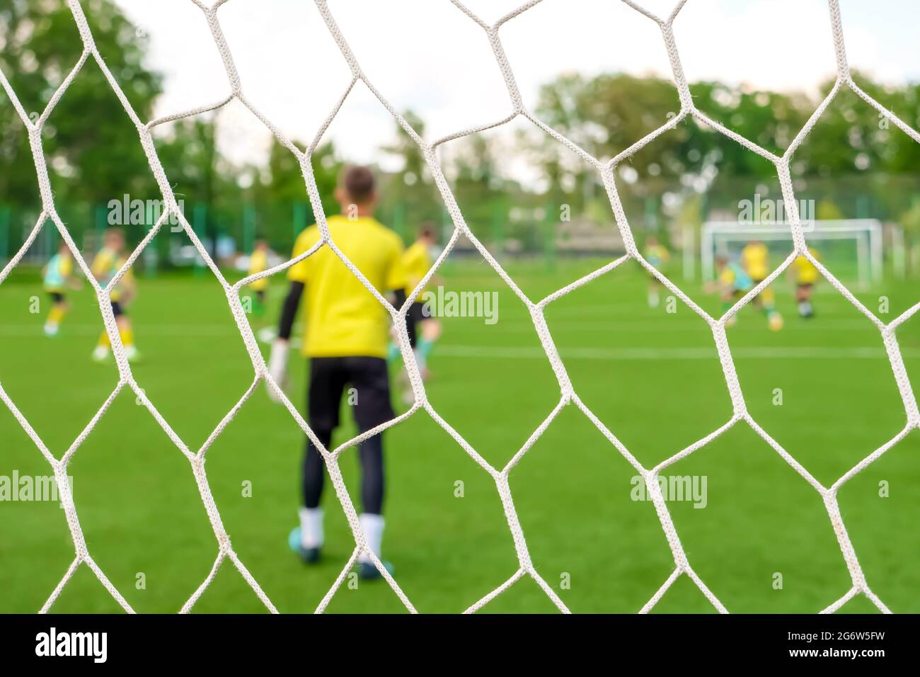 Goalkeeper back view goal post. Young team footballers play soccer