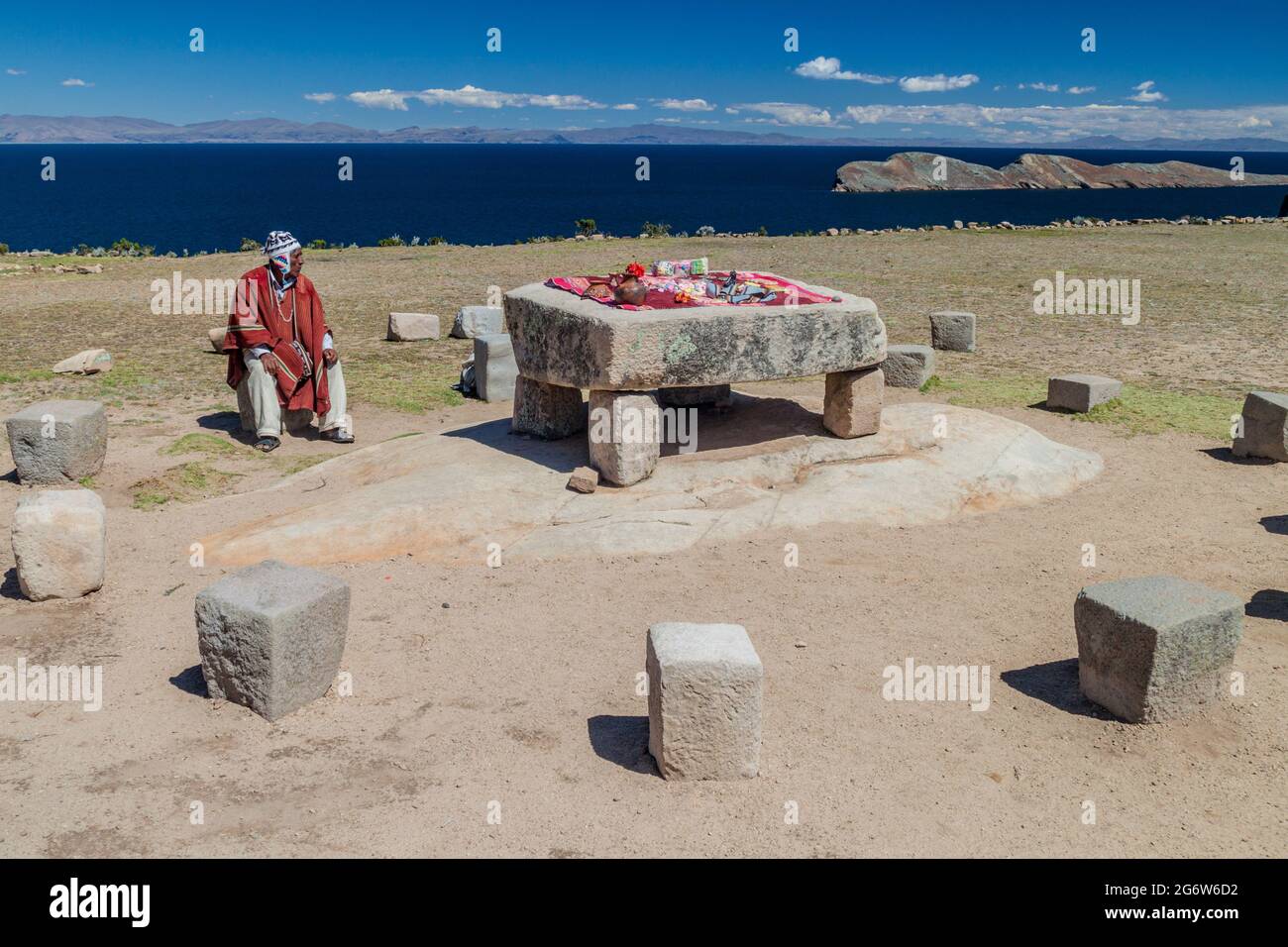 ISLA DEL SOL, BOLIVIA - MAY 12, 2015: Native man in traditional clothing next to the Ceremonial table used to be probably place of human sacrifices at Stock Photo