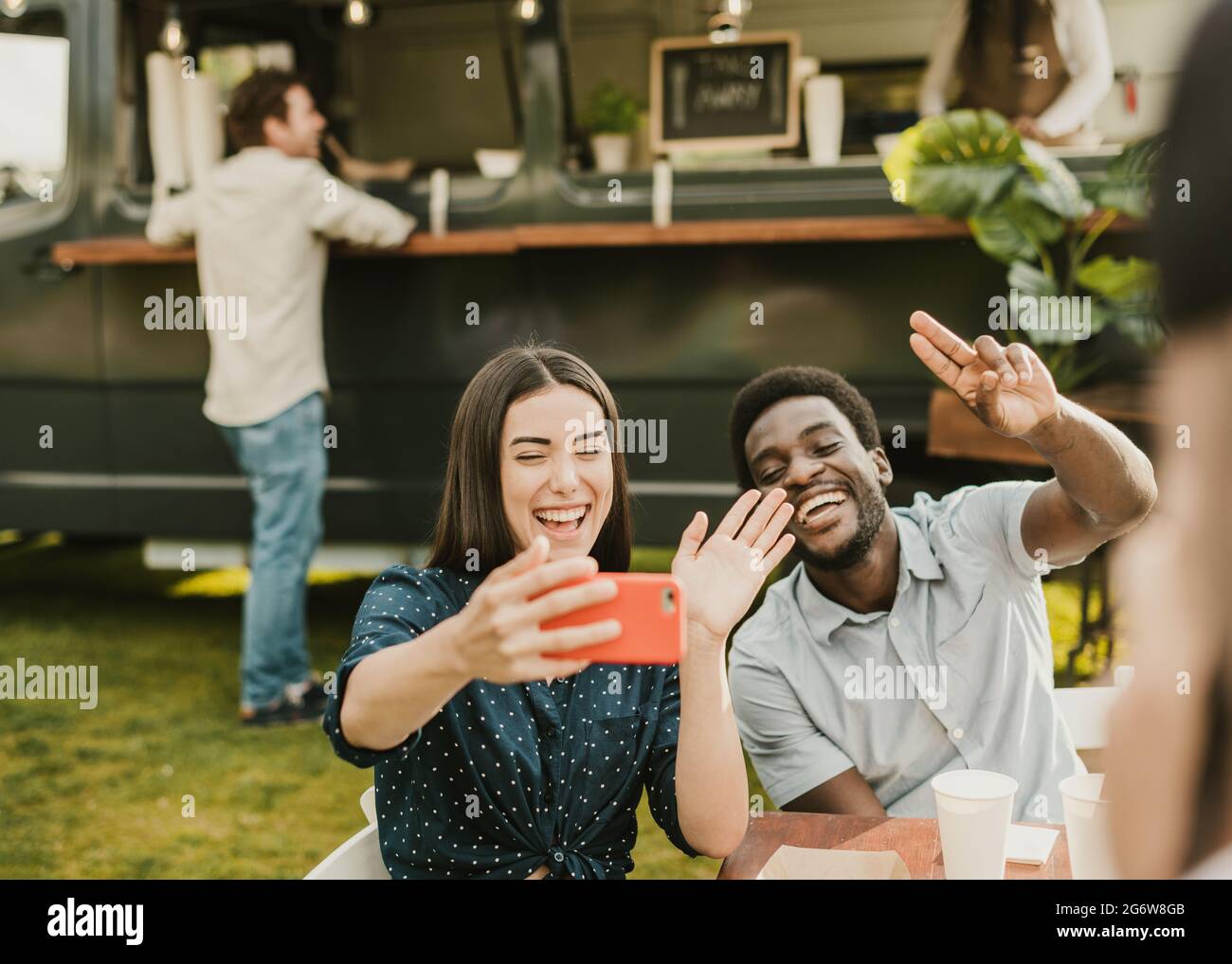 Multiracial friends having fun doing selfie eating at food truck outdoor - Focus on african man face Stock Photo