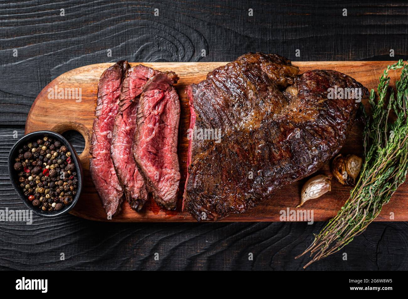 Grilled Butchers choice steak Onglet Hanging Tender beef meat on a cutting board. Black wooden background. Top View Stock Photo