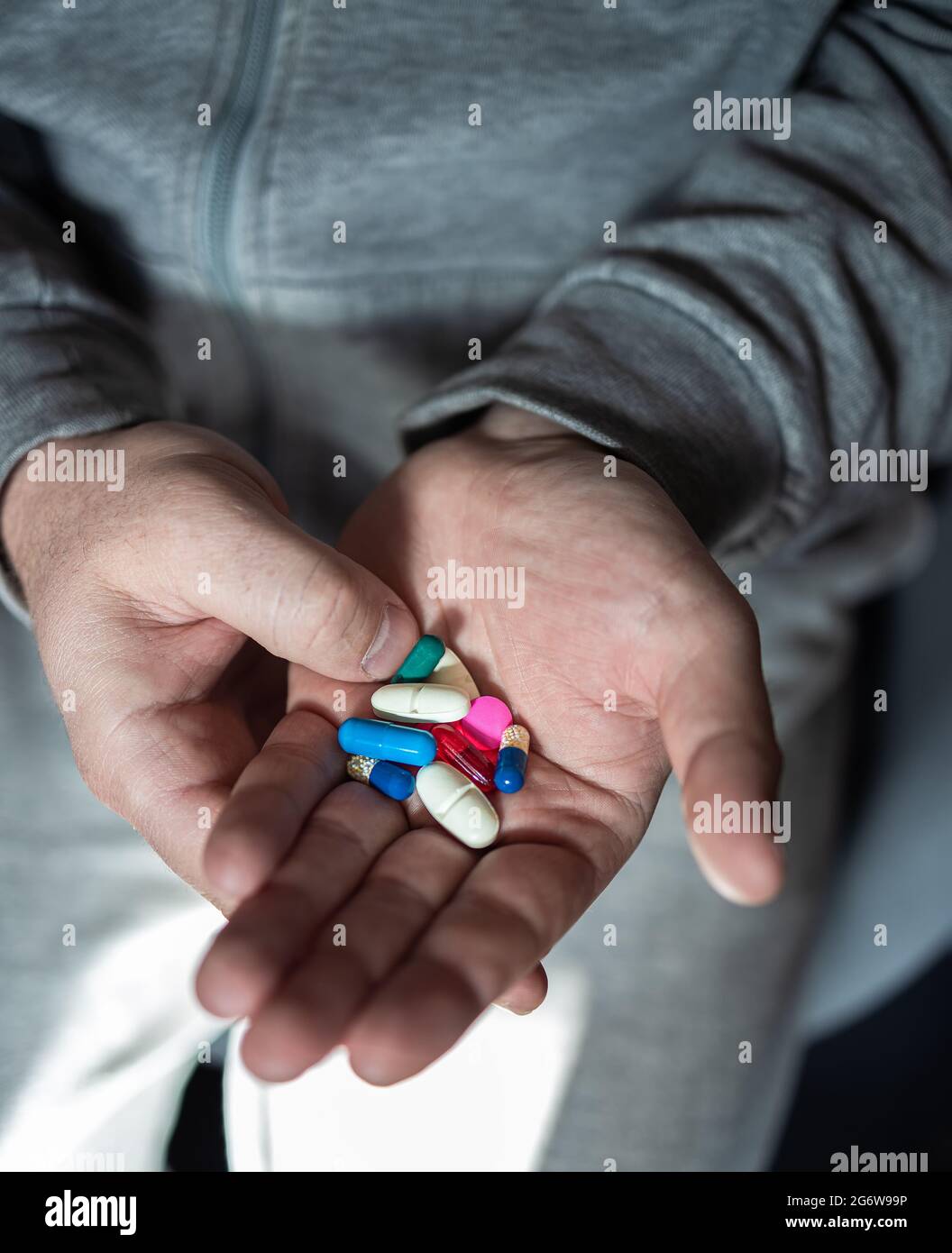 A man is holding various and multi-colored pills in his hands. Close-up. The concept of health protection and prevention of diseases with influenza an Stock Photo