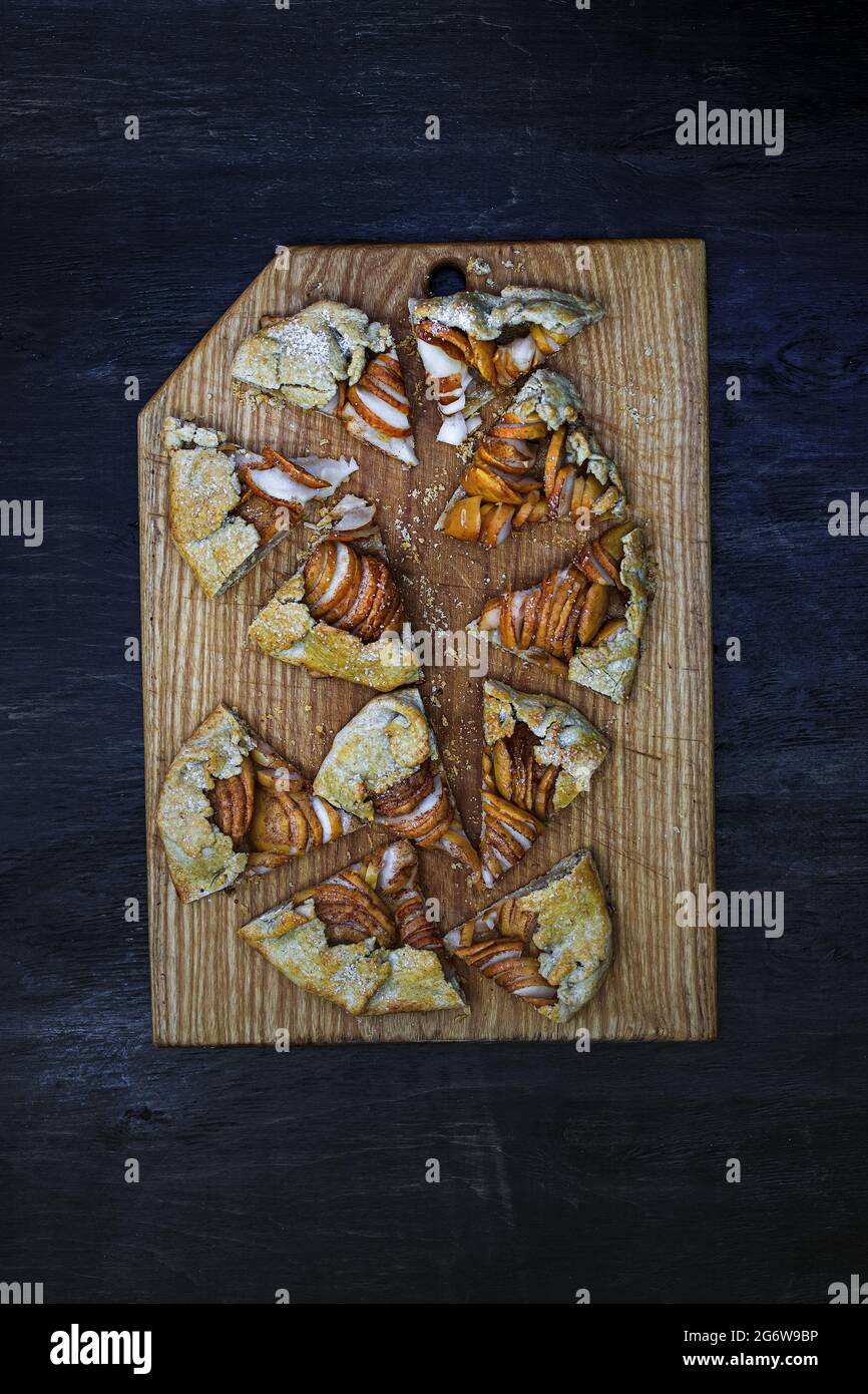 Apple galette - pie sliced into pieces on a wooden dark background. Copy space, flat lay Stock Photo