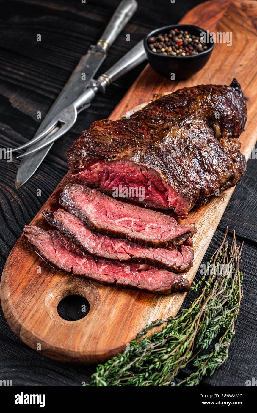 Grilled Butchers choice steak Onglet Hanging Tender beef meat on a cutting board. Black wooden background. Top View Stock Photo