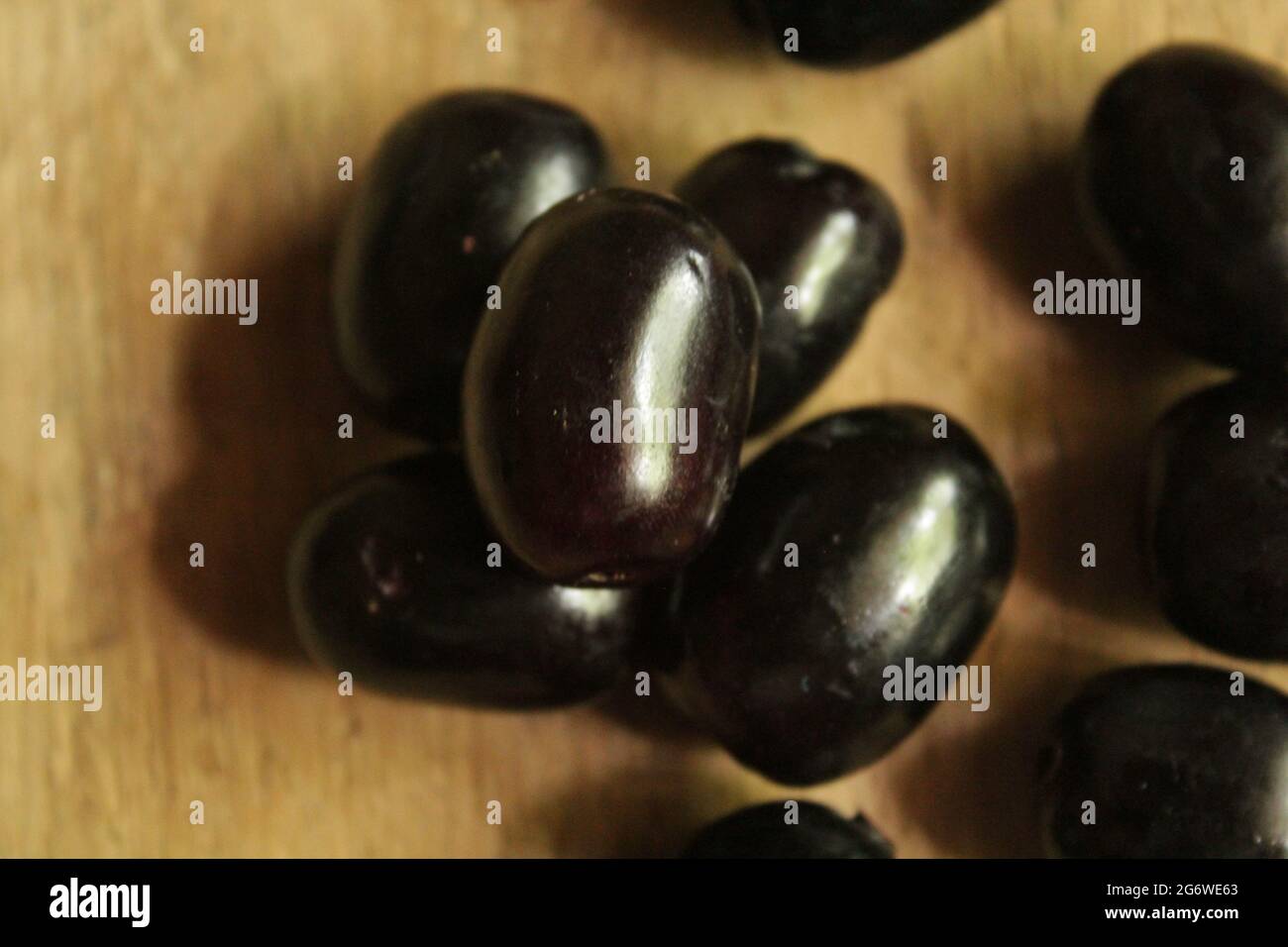 Java plum fruits or syzygium fruit on isolated wooden surface, top view, blue berry fruit, new image Stock Photo