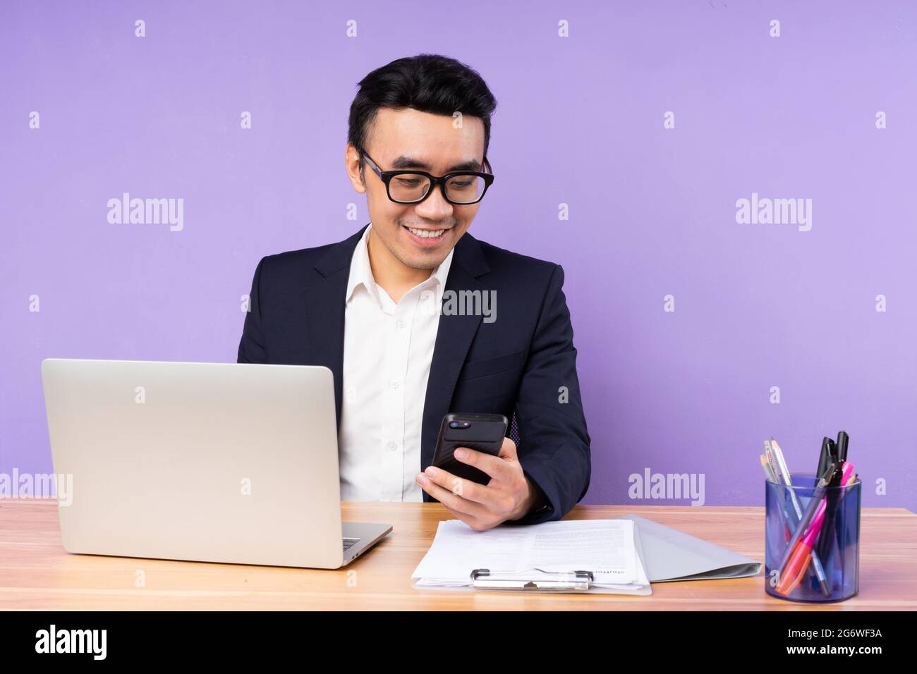 Asian businessman male portrait sitting on desk, isolated on purple background Stock Photo