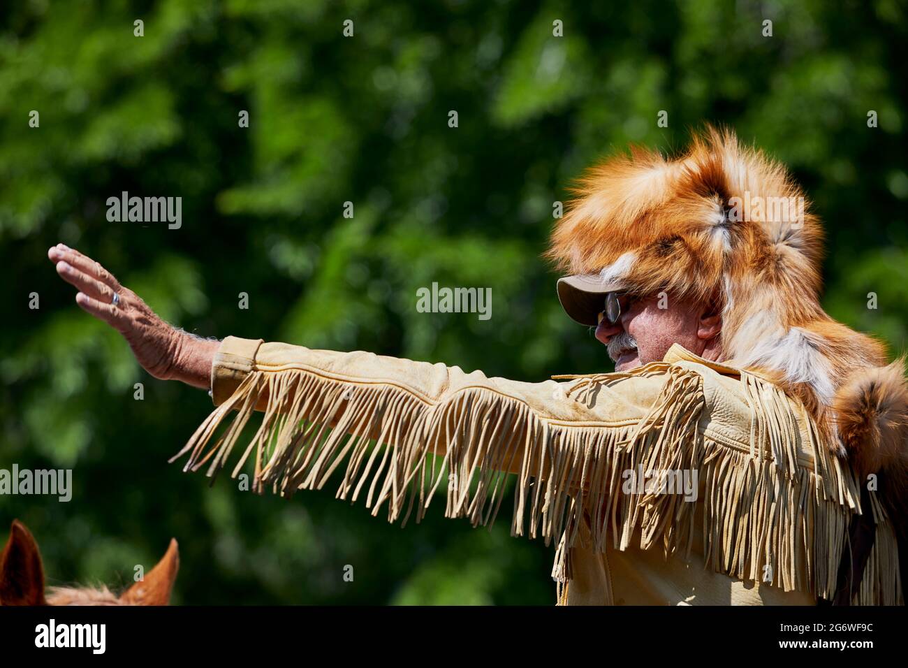 Prescott, Arizona, USA - July 3, 2021: Close up of a Mountain Man waving wearing a fur hat while riding a horse in 4th of July parade Stock Photo