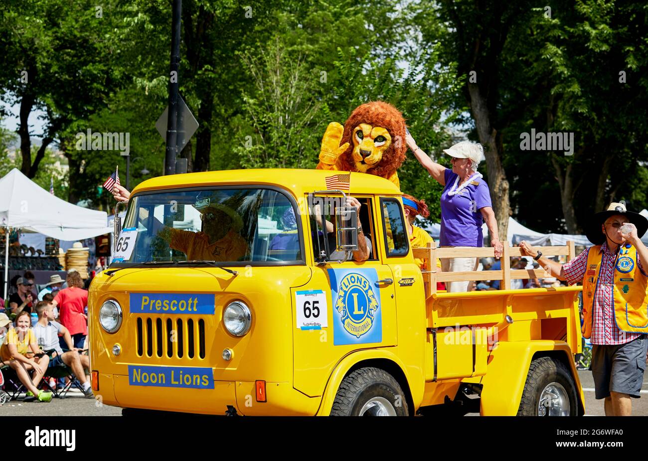 Prescott, Arizona, USA - July 3, 2021: Person in lions costume riding in a yellow antique truck Lions club float in the 4th of July parade Stock Photo