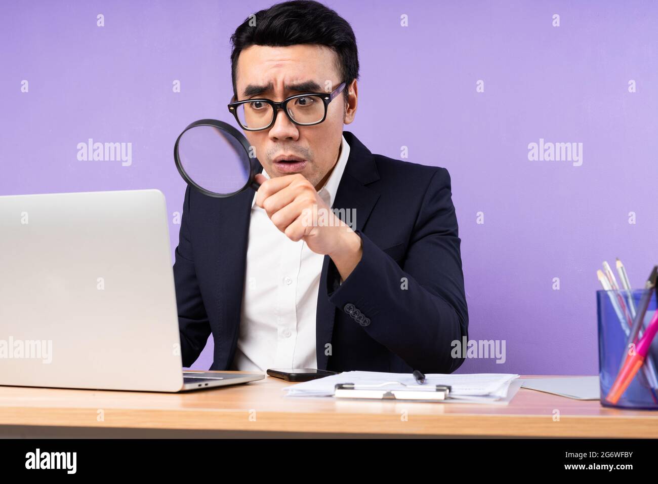 Asian businessman male portrait sitting on desk, isolated on purple background Stock Photo