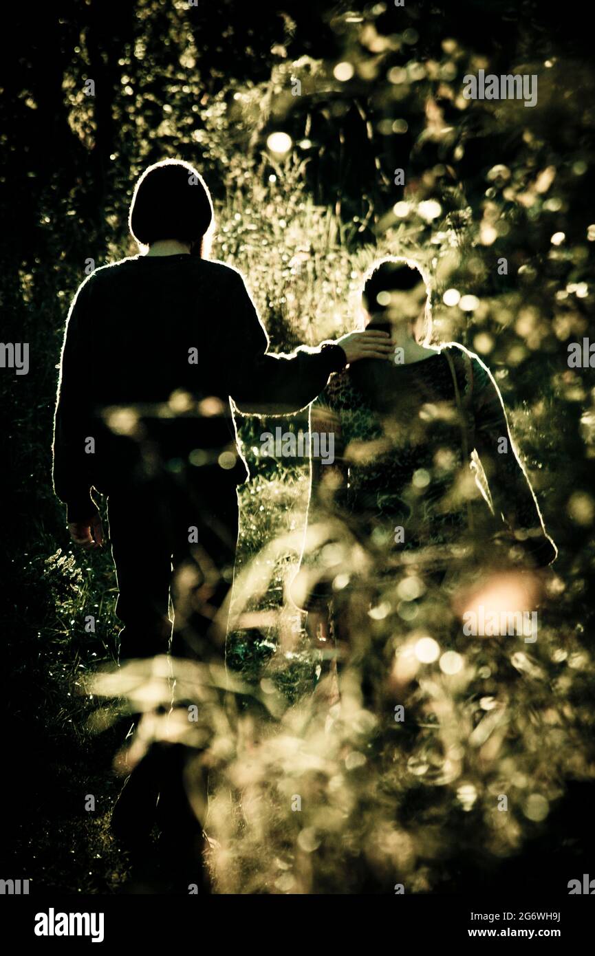 Silhouettes of young man and woman walking in the forest Stock Photo ...