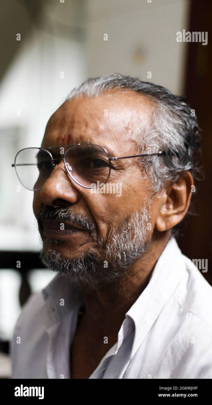 blurry portrait of a senior brown person with glasses looking at something casually under daylight Stock Photo