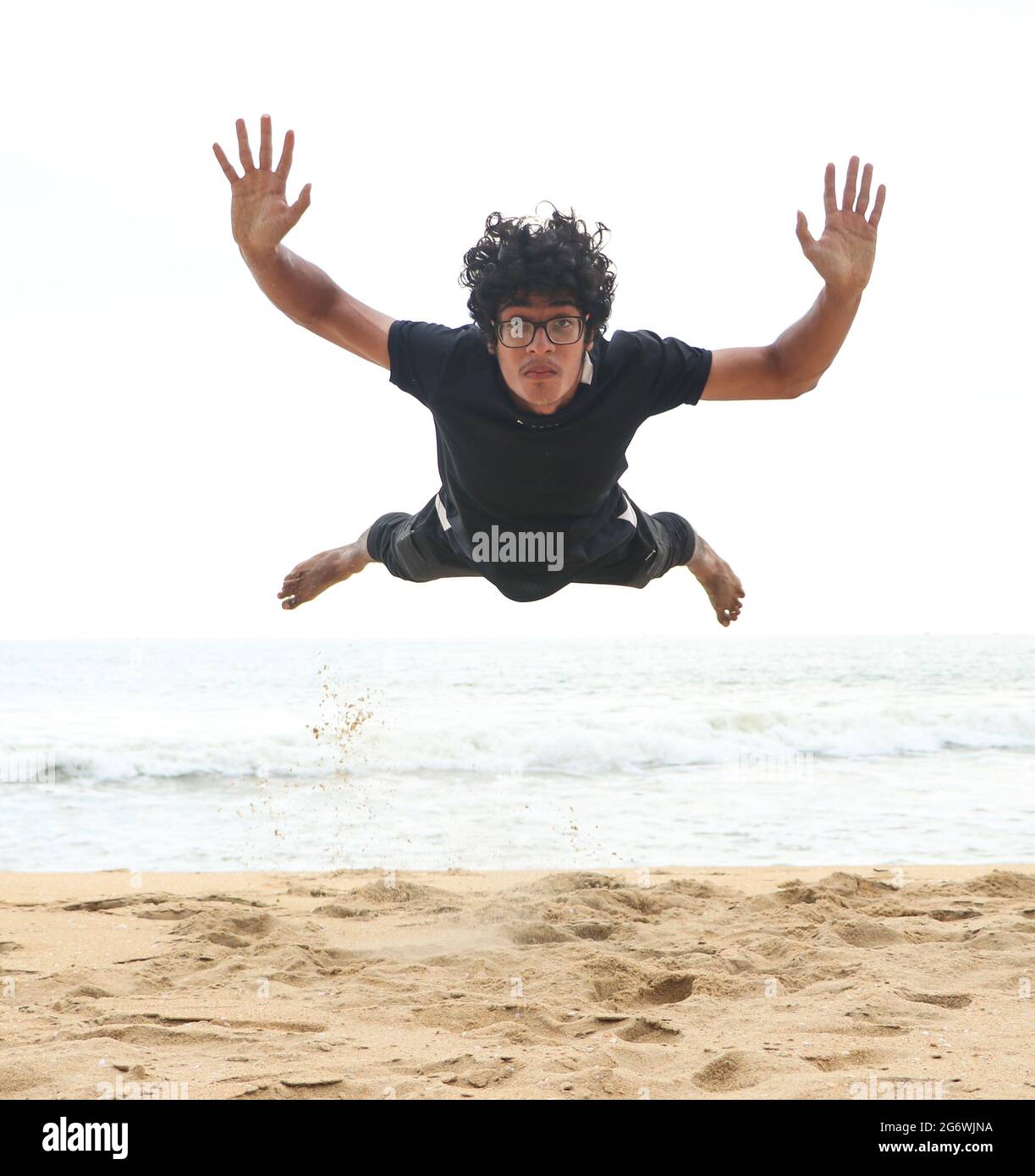 man jumping on the sandy beach after a taking push-up on a bright summer afternoon Stock Photo