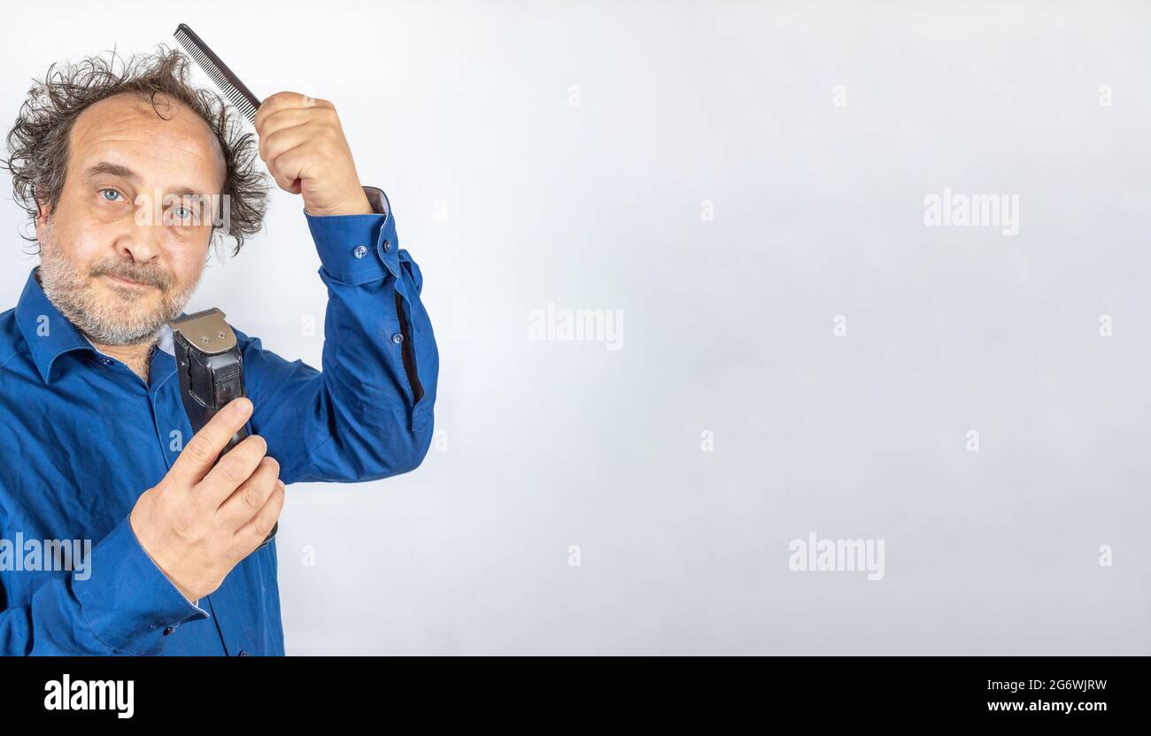 funny looking man with bad hair day facing decision comb or cut with hair trimmer. copy space to the right Stock Photo