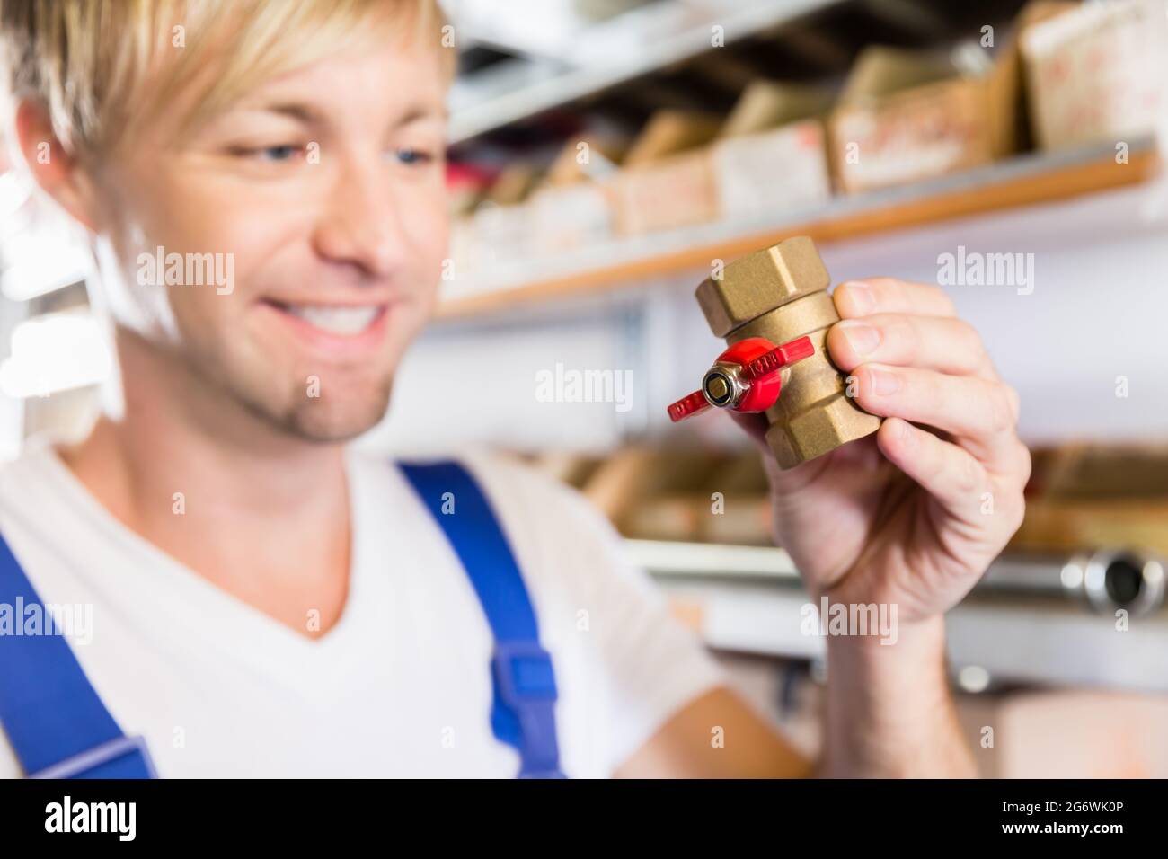 Close-up of the hands of a happy blue-collar worker holding two pipe fitting accessories in the storehouse of a modern sanitary ware shop Stock Photo