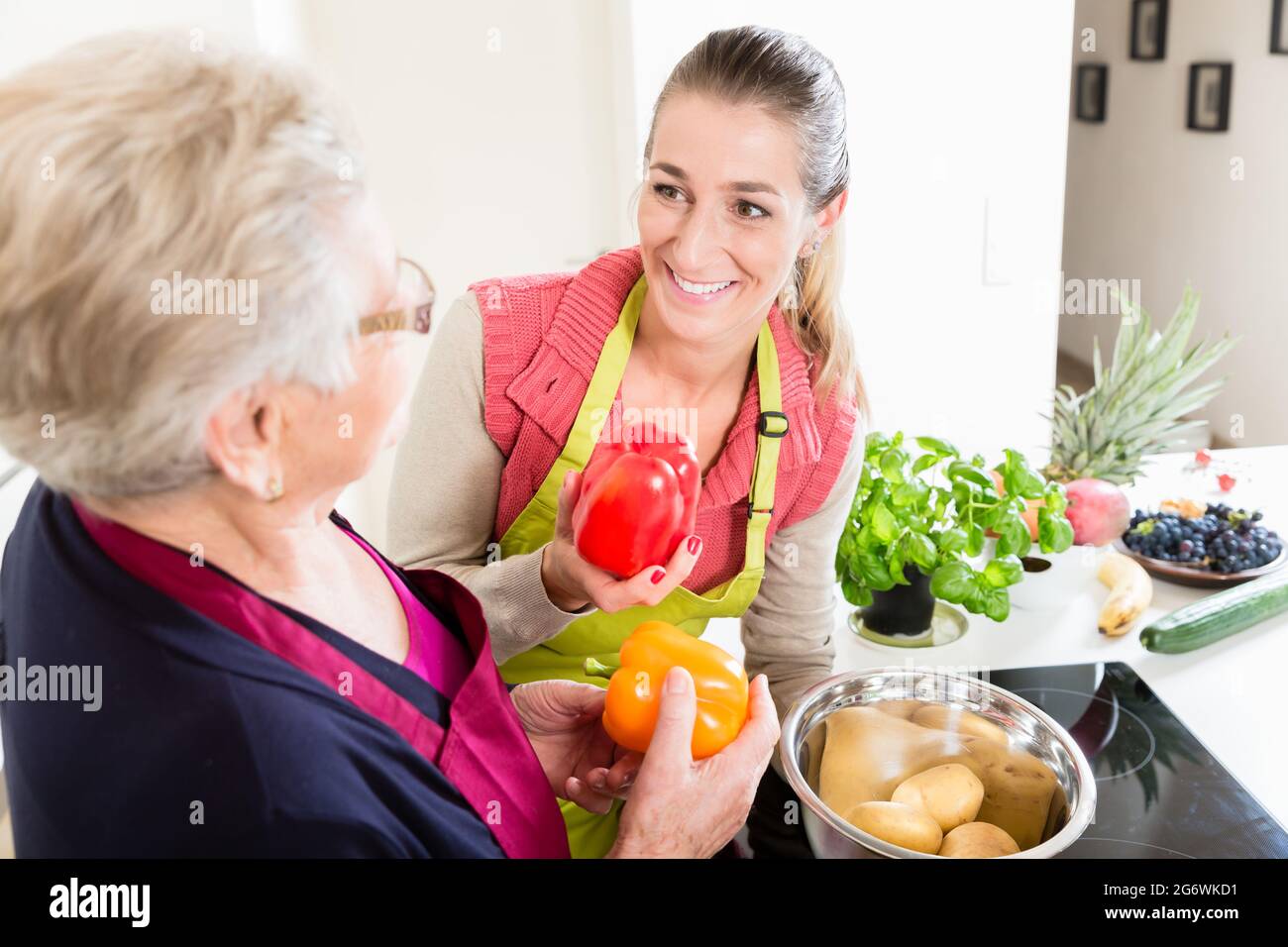 Mother in law explaining correct use of bell pepper in kitchen to her daughter in law once again Stock Photo