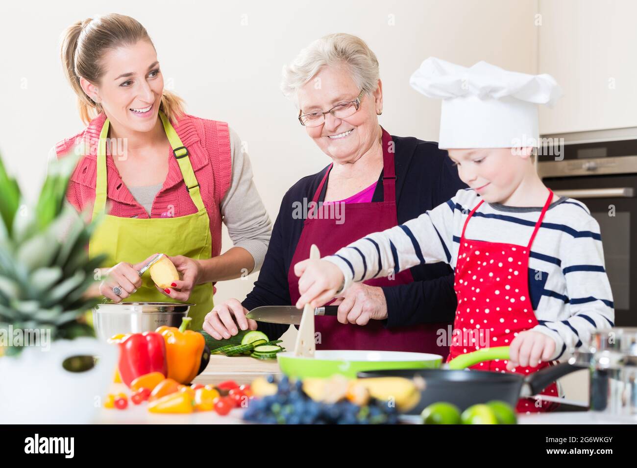 Granny, mum and son talking while cooking together in kitchen Stock ...