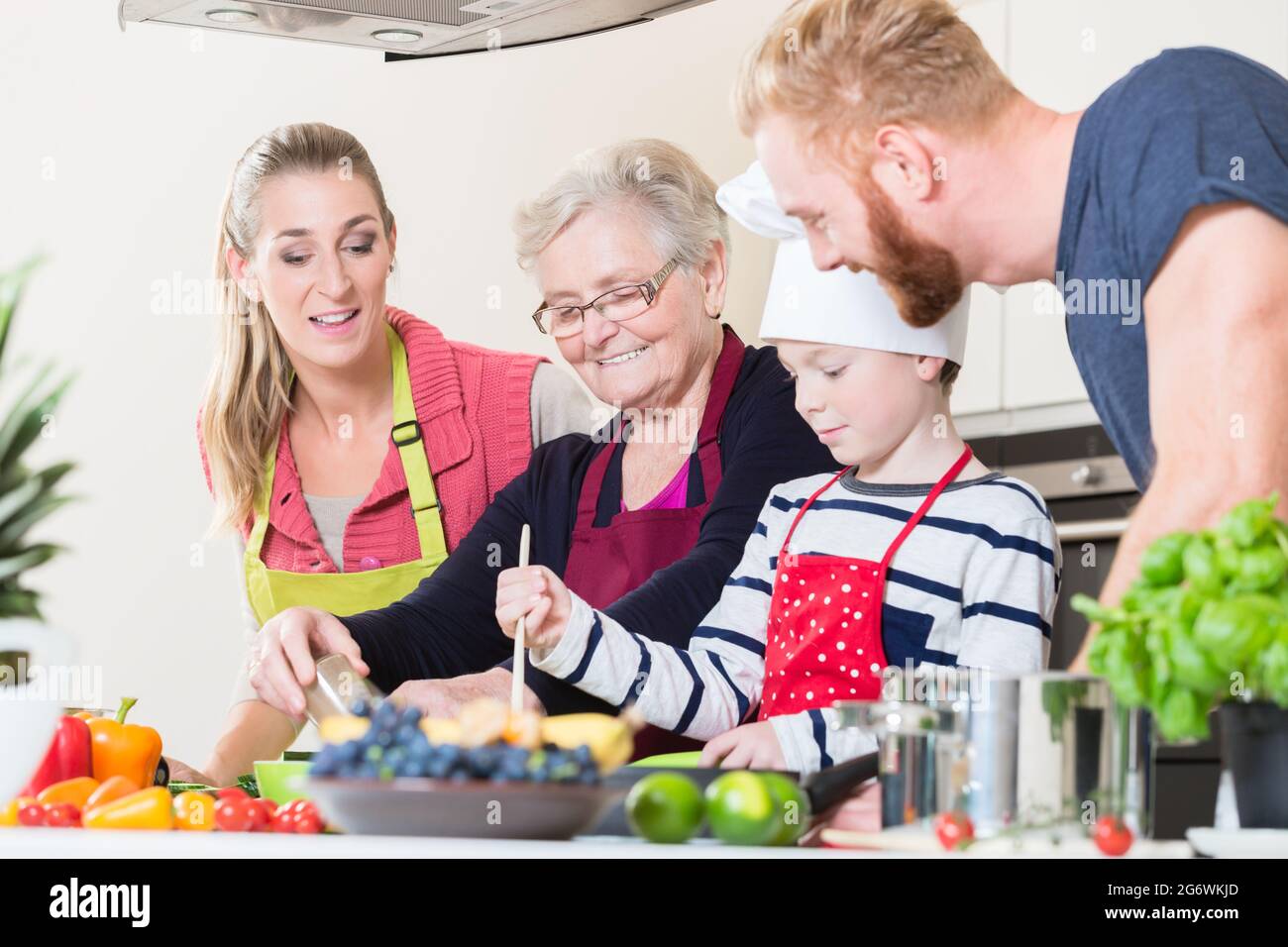 Family cooking in multigenerational household with son, mother, father and grandfather Stock Photo