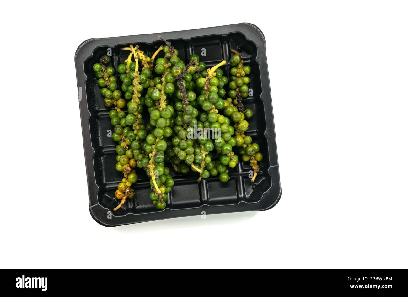 Isolated organic fresh bunch of pepper in the plastic black tray on white background. Fresh pepper in a black tray for sale in the market. Top view im Stock Photo