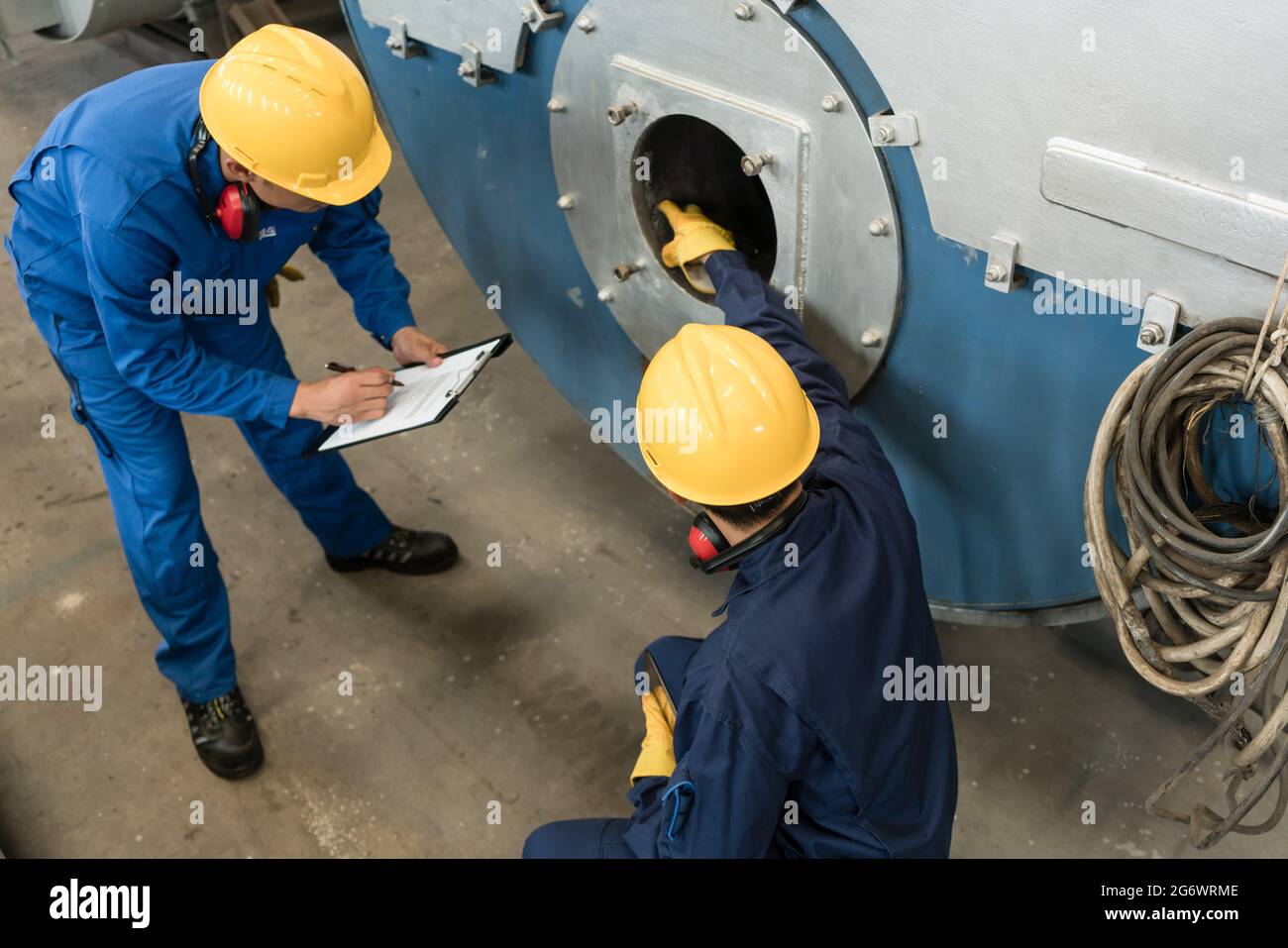 Asian expert checking the quality requirements of manufactured industrial steam boilers Stock Photo