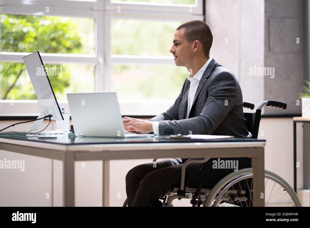 Handicapped Businessman Using Laptop Computer In Office Stock Photo